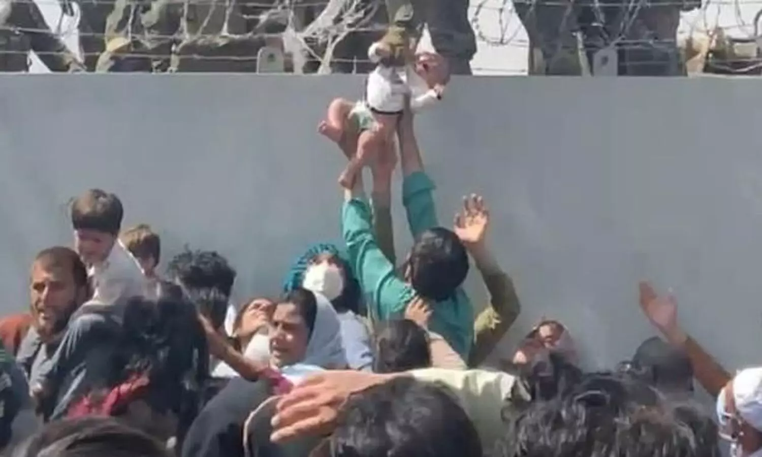Baby passed over a wall at Kabul airport reunited with family