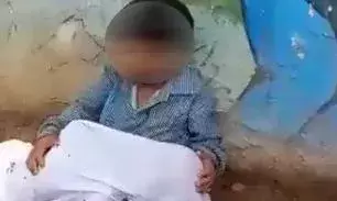 8-yr-old boy sits with younger brothers body in lap outside hospital as father looks for ambulance